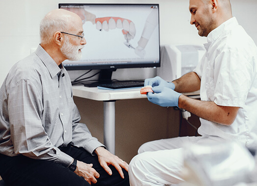 A dentist explaining a denture to an older man.