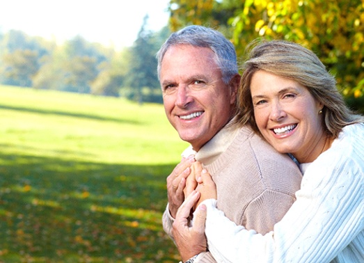 An older couple hugging outside.