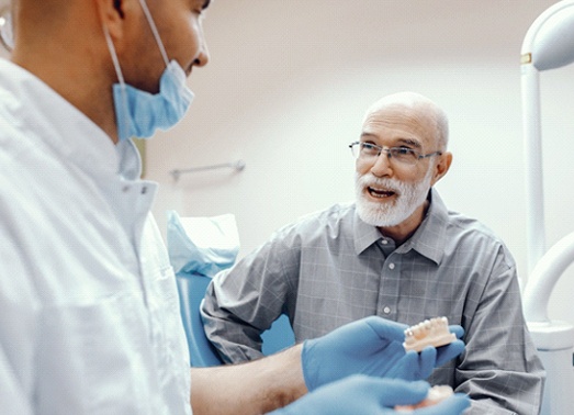 An older man speaking with a dentist.