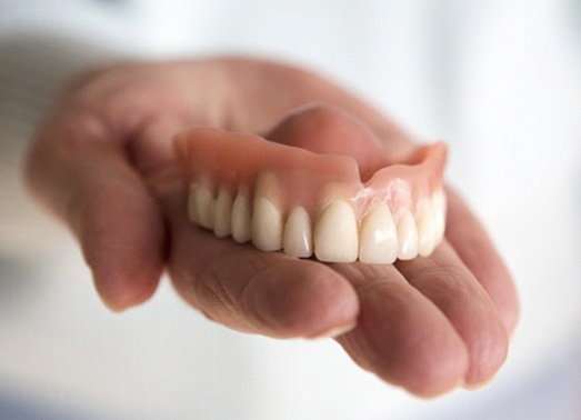 A person holding a brand-new denture.