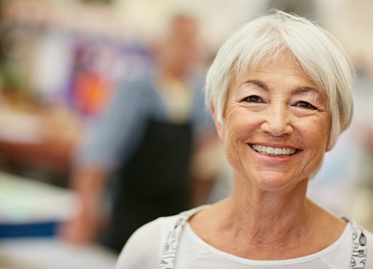 Woman smiling after gold denture tooth replacement