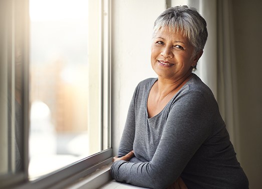 Woman smiling after silver denture tooth replacement