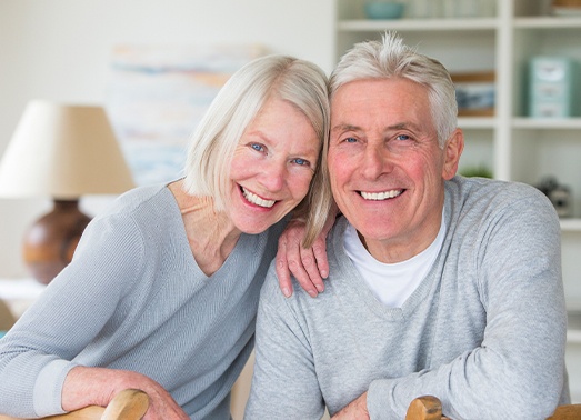 Man and woman smiling after cast metal partial denture tooth replacement