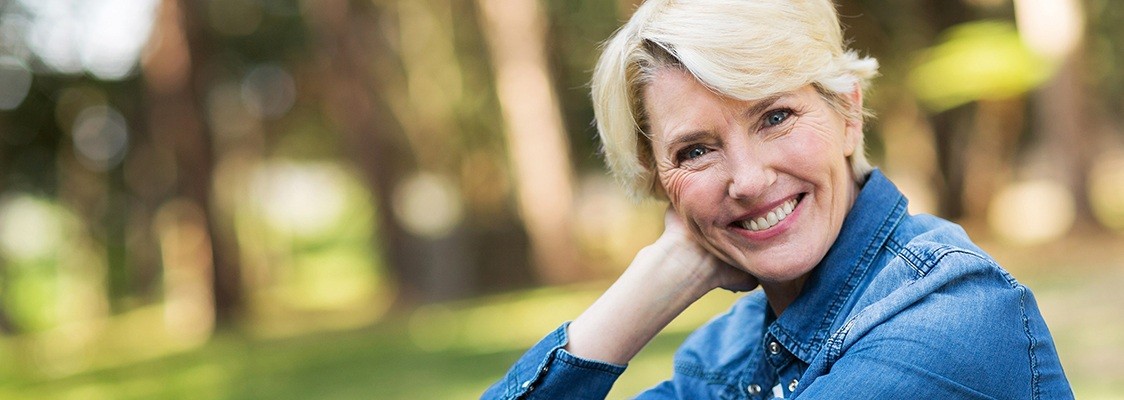 Woman smiling after tooth extractions and denture restoration