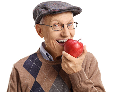 An older man biting into an apple.