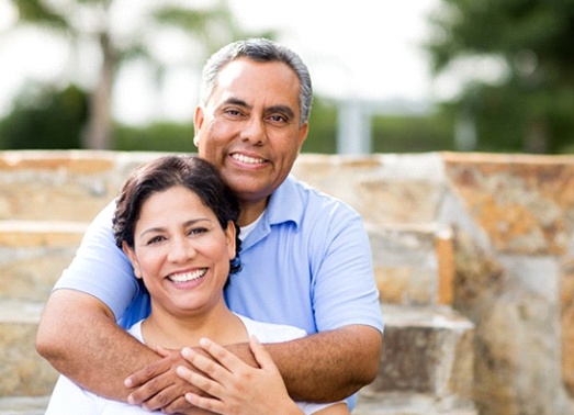 An older couple hugging outside.